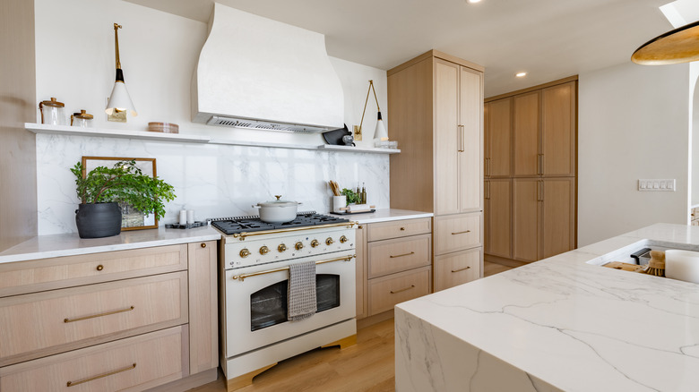 A very neat kitchen with pale wood cabinets and a cream range oven.