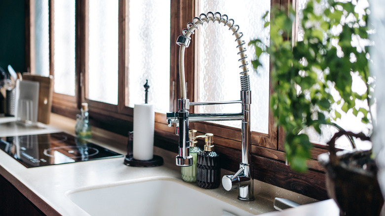 A kitchen sink with curved tap and pretty decorative soap bottles.