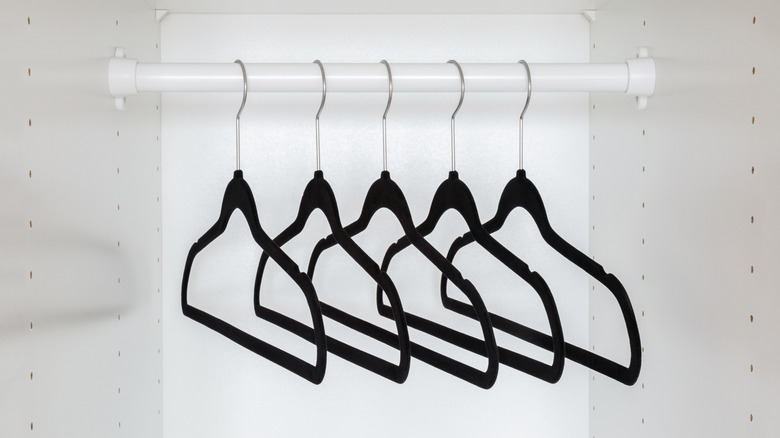 An empty closet with matching black velvet hangers in it.