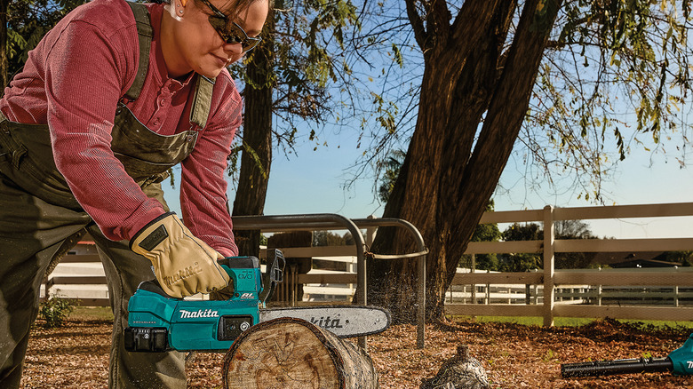 A person using Makita's 18V LXT 10-inch Top Handle Chain Saw