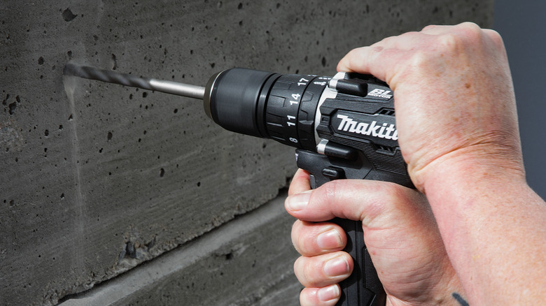 A person drilling into concrete with Makita's 18V LXT Sub-Compact Lithium-Ion Brushless Cordless ½-inch Hammer Driver Drill