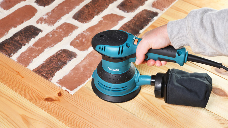 Close-up of a person using a Makita wood sander