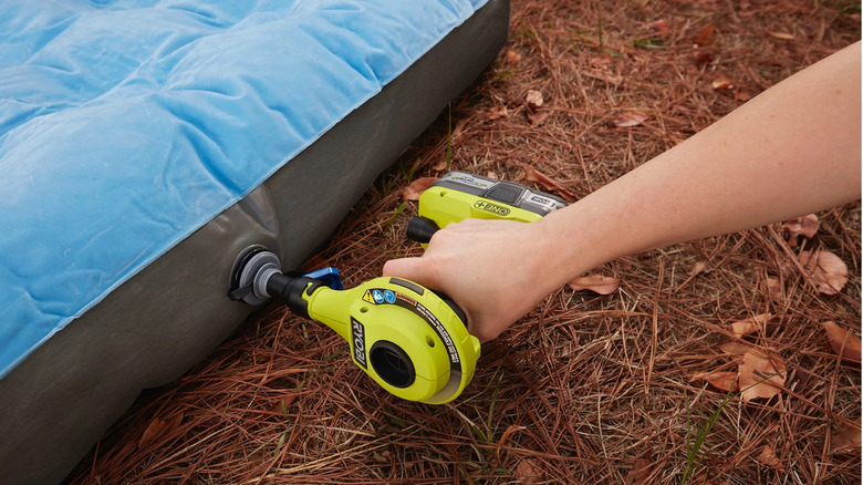 A person blowing up an air mattress with Ryobi's 18V One+ Cordless High Volume Inflator