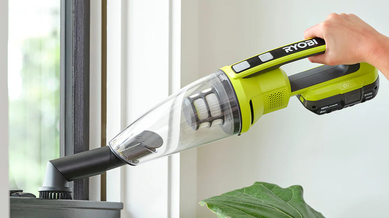 A person dusting a window with Ryobi's 18V One+ Hand Vacuum
