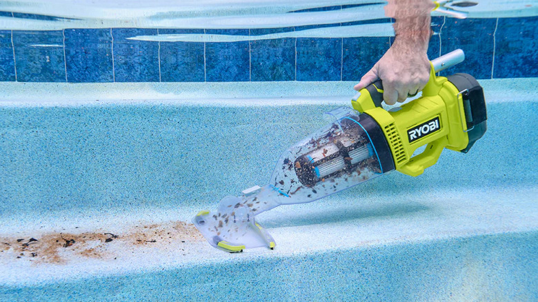 A person cleaning an underwater swimming pool step with Ryobi's 18V One+ Handheld Cordless Pool Vacuum Cleaner