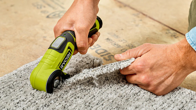 A person cutting carpet with Ryobi's USB Lithium Power Cutter Kit