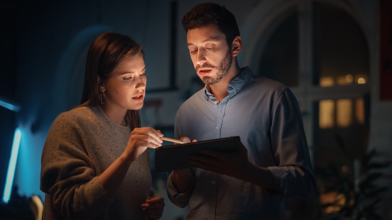 Couple looking at tablet in the dark