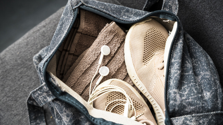 The inside of a gym bag with trainers, clotes and headphones.