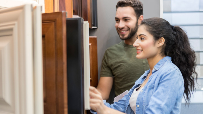 Two people shopping for kitchen cabinets in a home store