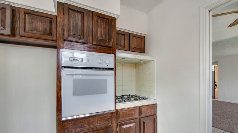 A kicthen with dated wood cabinets and appliances