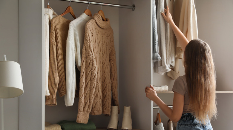 A woman organizing winter closet with sweaters