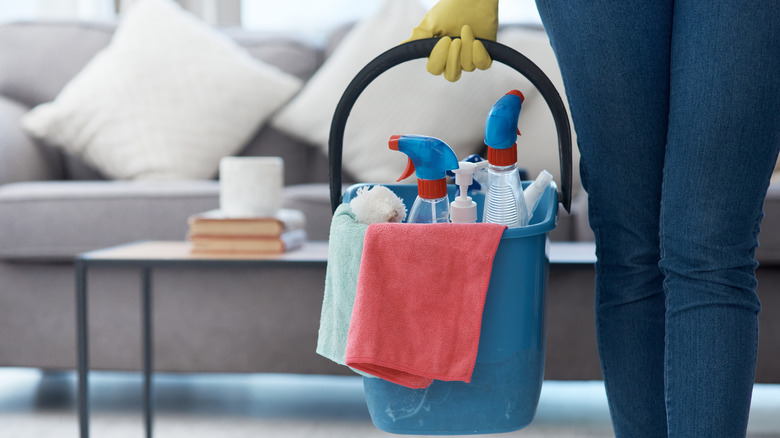 Person holding bucket of cleaning supplies