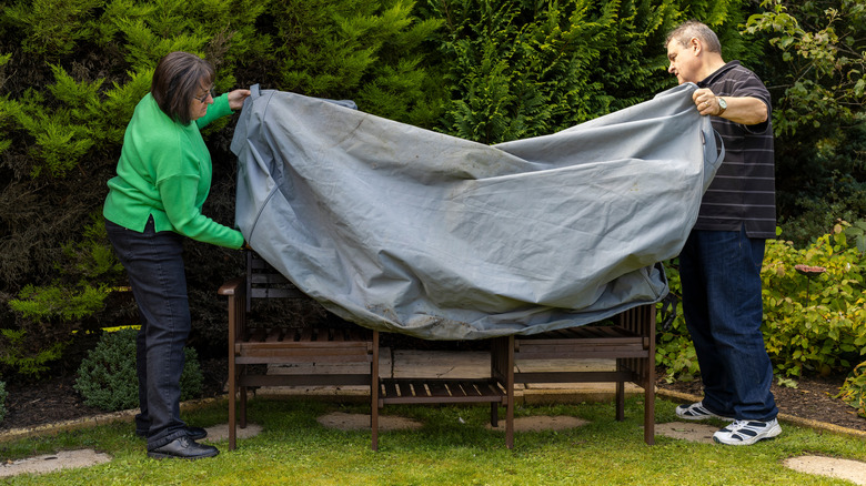 Couple covering outdoor furniture in backyard