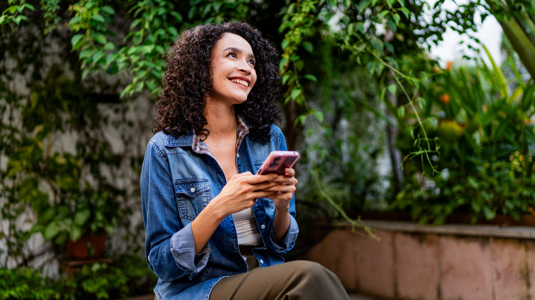 A young woman using her smartphone while sitting in the garden