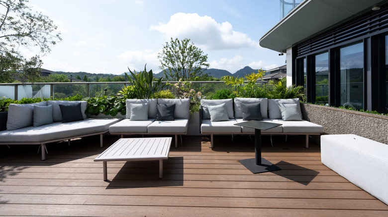 A modern rooftop terrace with lots of greenery in planters around the edge