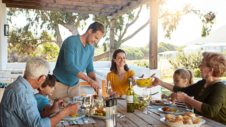 A family enjoying a meal outdoors on a deck