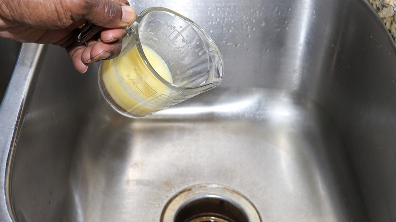 Solidified grease or oil being poured down drain