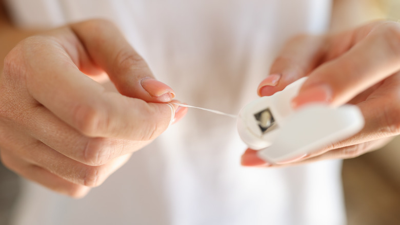 Person taking dental floss from container