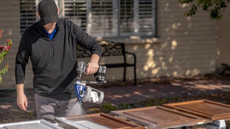 A person spray painting cabinets= doors using Graco's TrueCoat 360 Drill-Powered Paint Sprayer