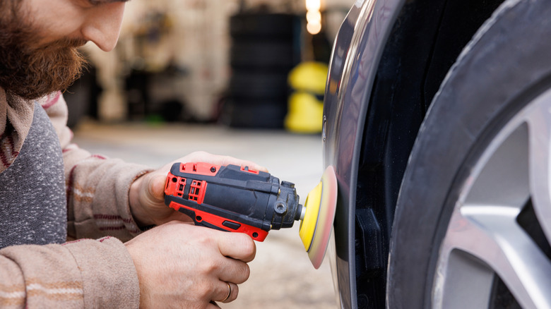 A person using a drill and polishing wheel to buff a car