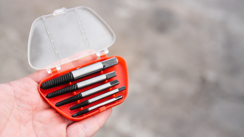 A person holding a set of screw extractor drill bits