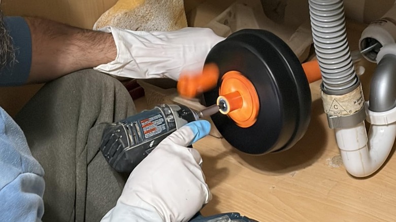 Close-up of a person using BACEYIOU's drill-ready drain auger in use