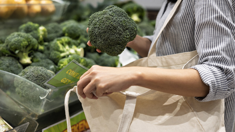 person putting produce in reusable bag
