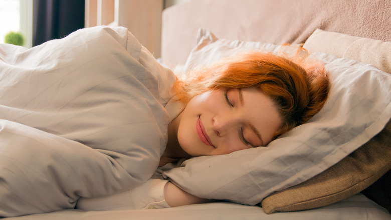 woman sound asleep on a cozy bed with pink linens