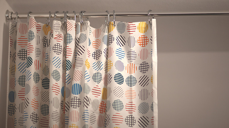 A plastic shower curtain with circular patterns hanging in bathroom