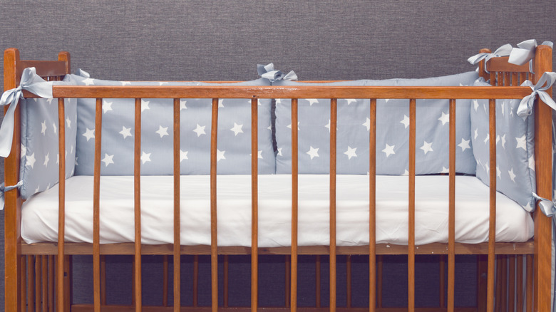 A wooden crib with blue padding featuring star shapes