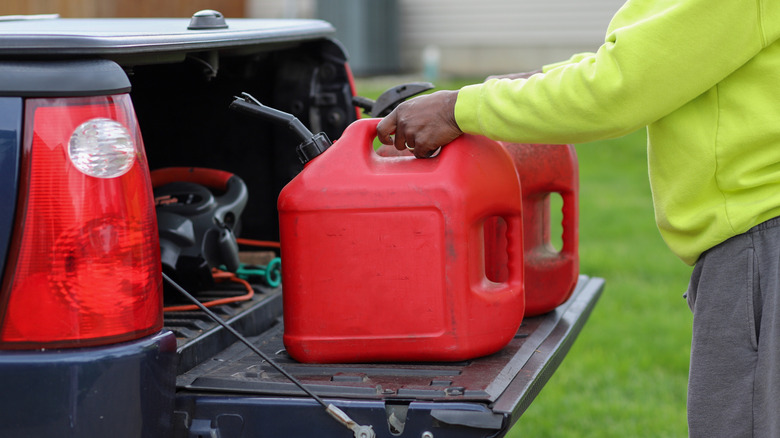 A person putting two gas cans into a truck