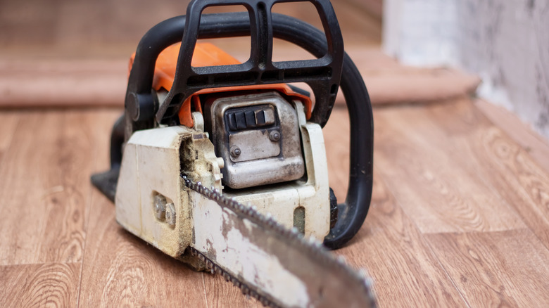 Gas-powered chainsaw sitting on wooden floor