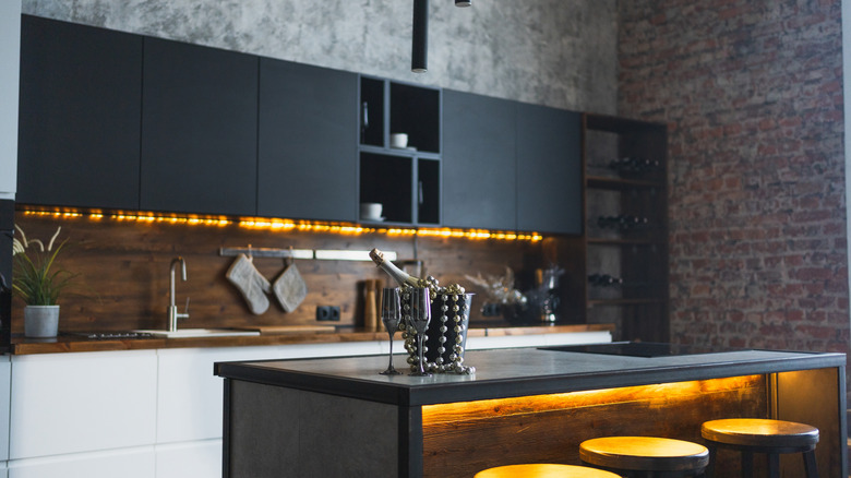 Dark minimalist kitchen with empty brick wall