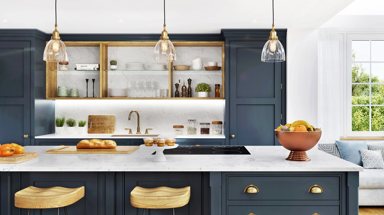 A kitchen with gold-toned open shelves and blue pantries