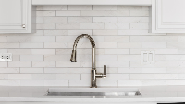 Closeup of kitchen sink fixture with subway tile backsplash