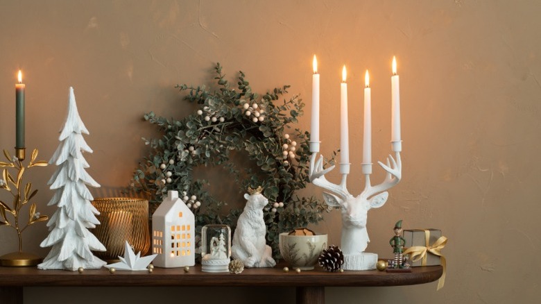 A mantle filled with white decor including a large deer head candleholder