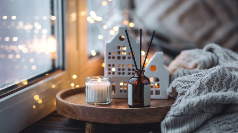 An incense diffuser on a table with a candle and decorative houses