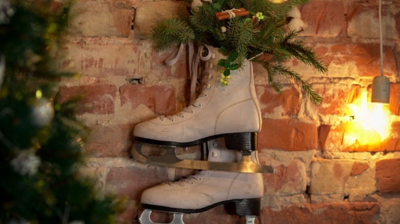 Ice skates hanging on wall with greenery placed in them