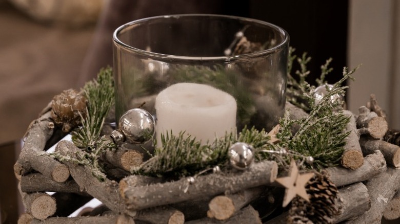 Candle holder with raw twig pieces and greenery