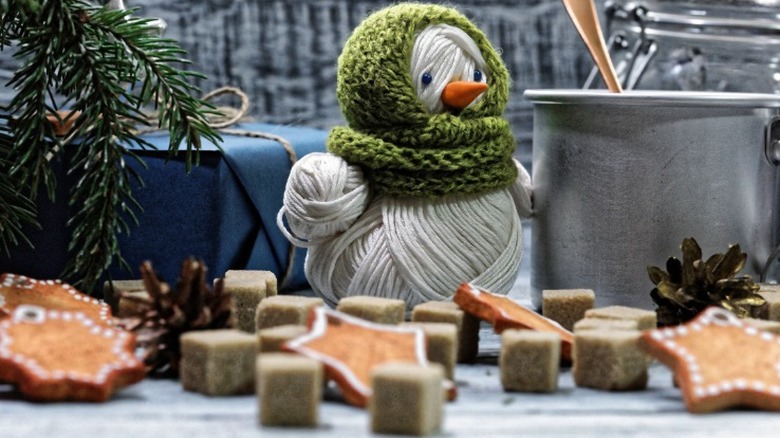 Handmade yarn snowman decor alongside wintry cookies