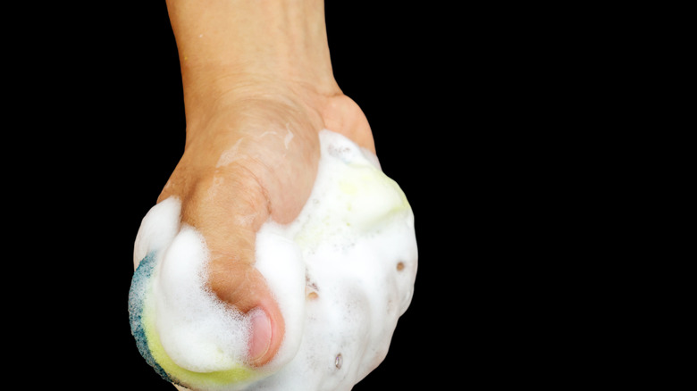 Woman is seen wiping down an iron with a soapy sponge