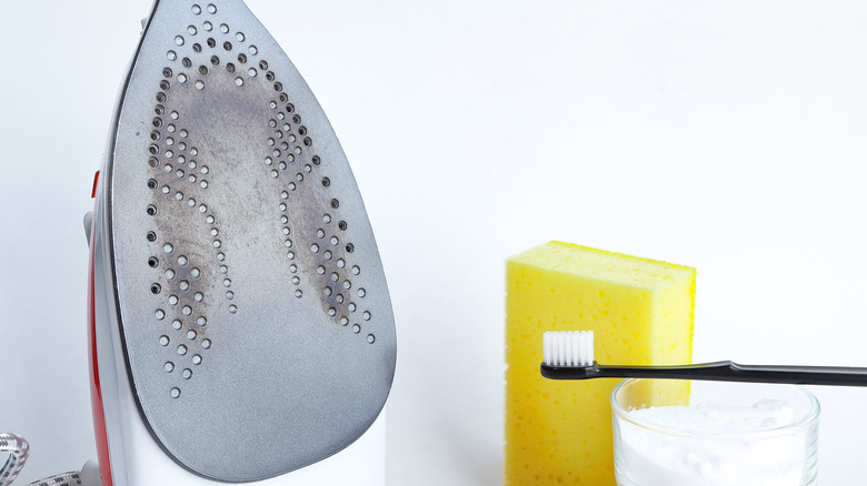 A dirty iron rests near a class of baking soda paste and a toothbrush