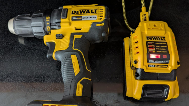 DeWalt drill driver, battery, and charger, on dark surface