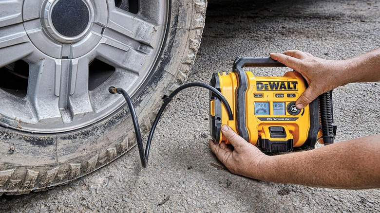 Man using DeWalt air compressor to fill up worn and dirty tires