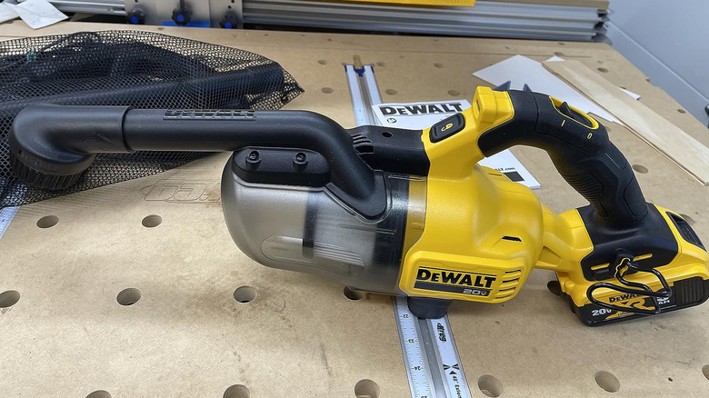 Handheld DeWalt vacuum beside product manual and accessory bag on worktop