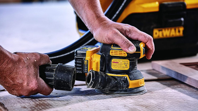 Man attaching accessory to DeWalt orbital sander for wood project