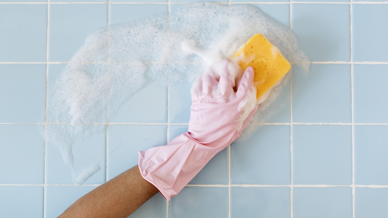 person cleaning tiles with sponge