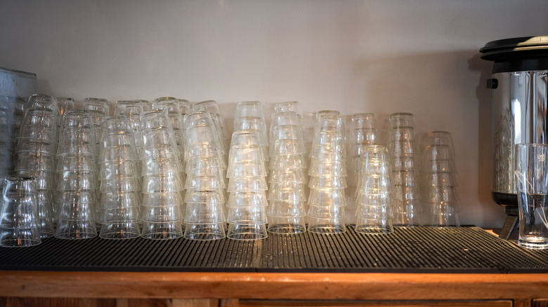 A countertop with lots of drinking glasses stacked
