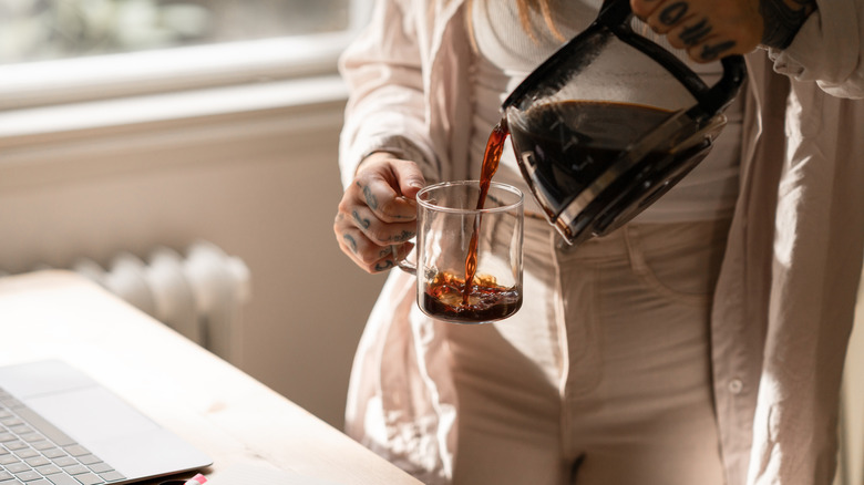 A woman pouring a cup of coffee