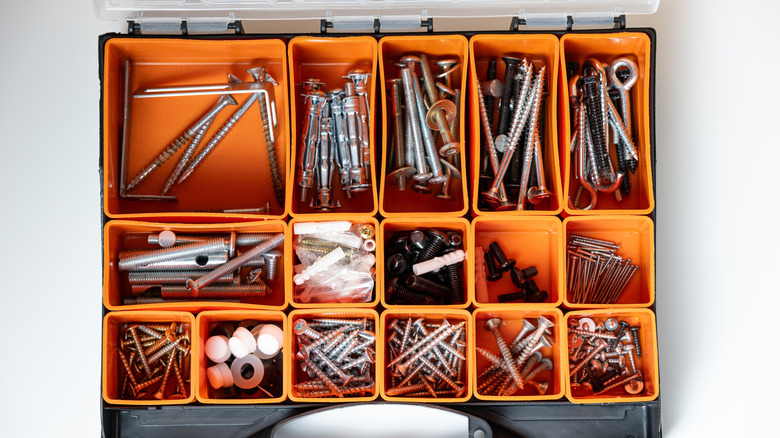 An organizer box filled with various nails, screws, and other fixings
